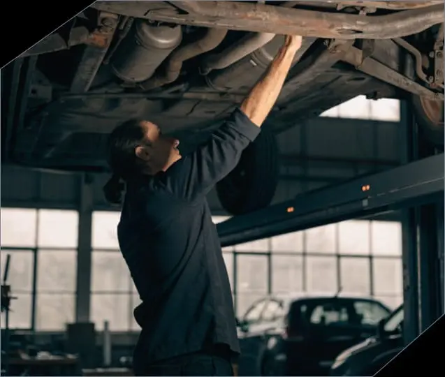 Mecánico trabajando bajo un vehículo elevado en el taller